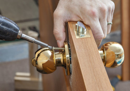 Install the door handle with a lock, Carpenter tighten the screw, using an electric drill screwdriver, close-up.